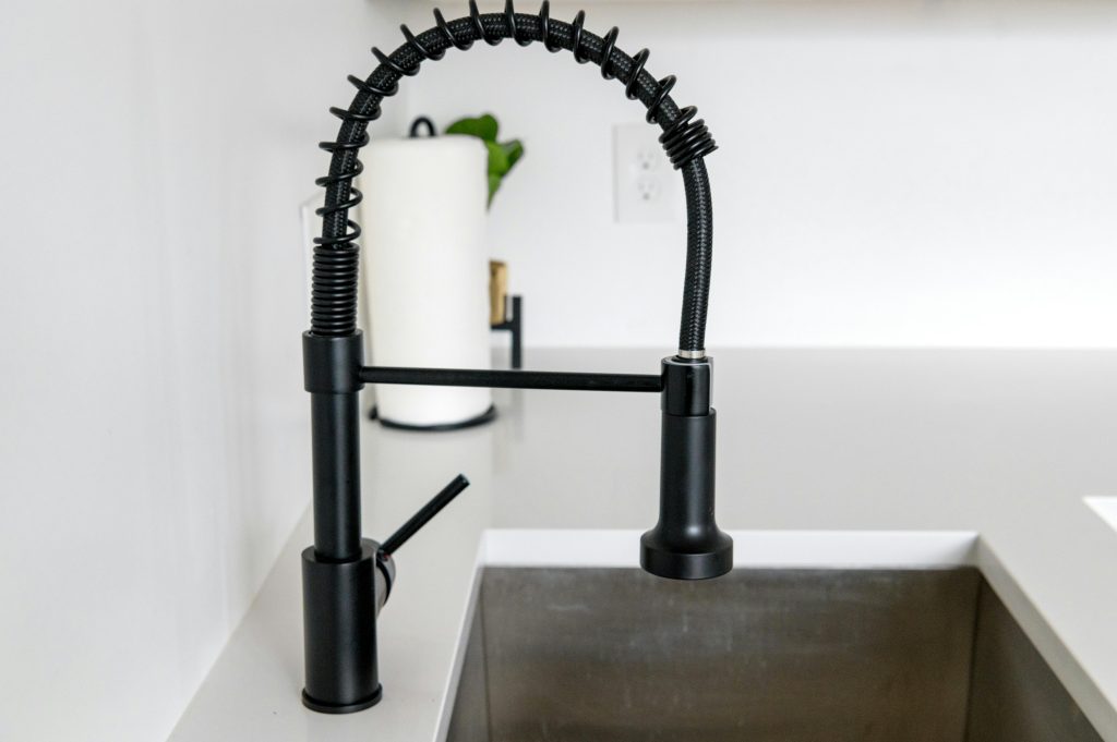 pexels-photo-6253786-6253786 Sleek black faucet on white countertop in modern kitchen. Ideal for minimalist and contemporary designs.