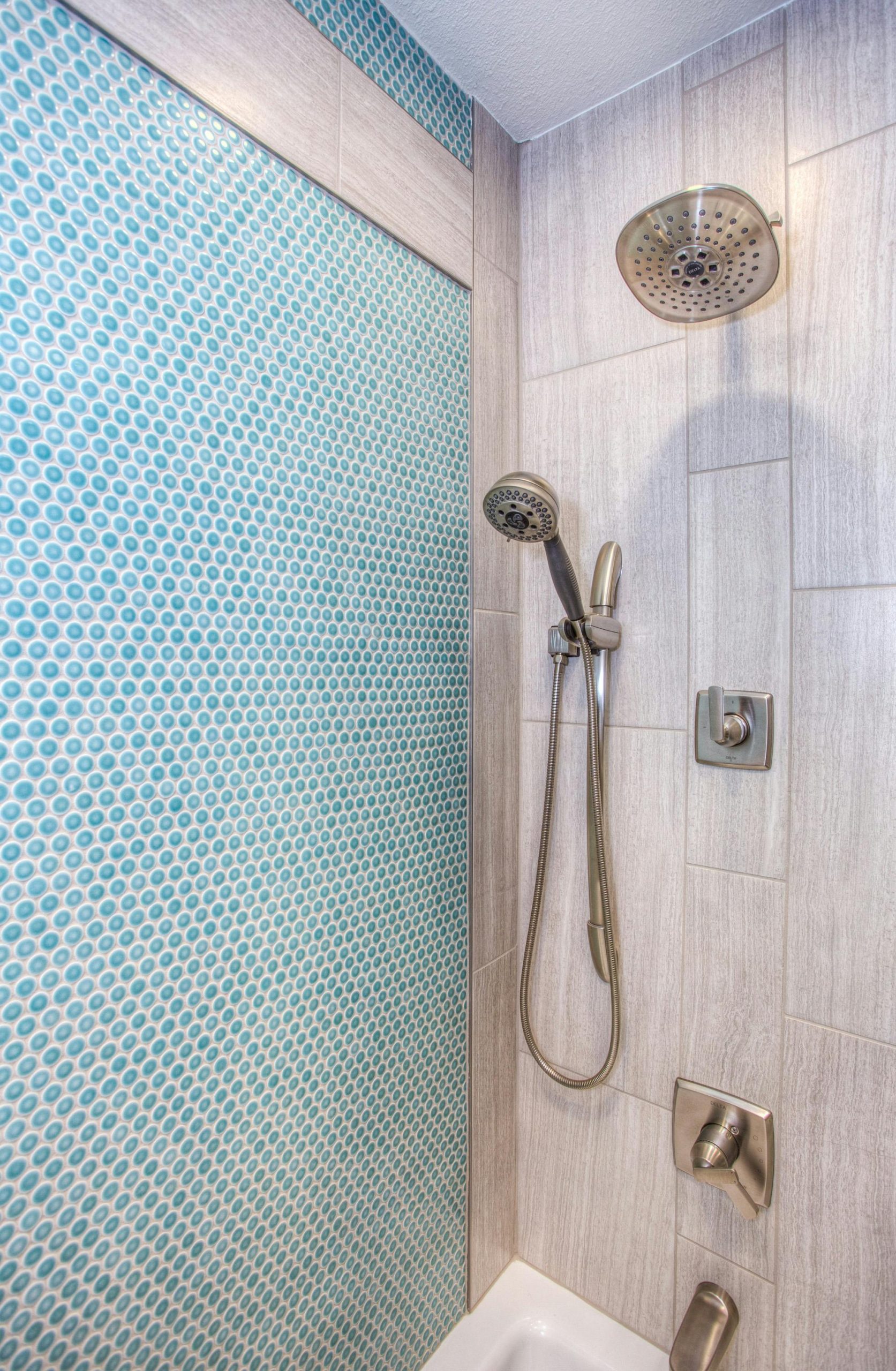 Elegant shower design featuring blue mosaic tiles and stainless steel fixtures.