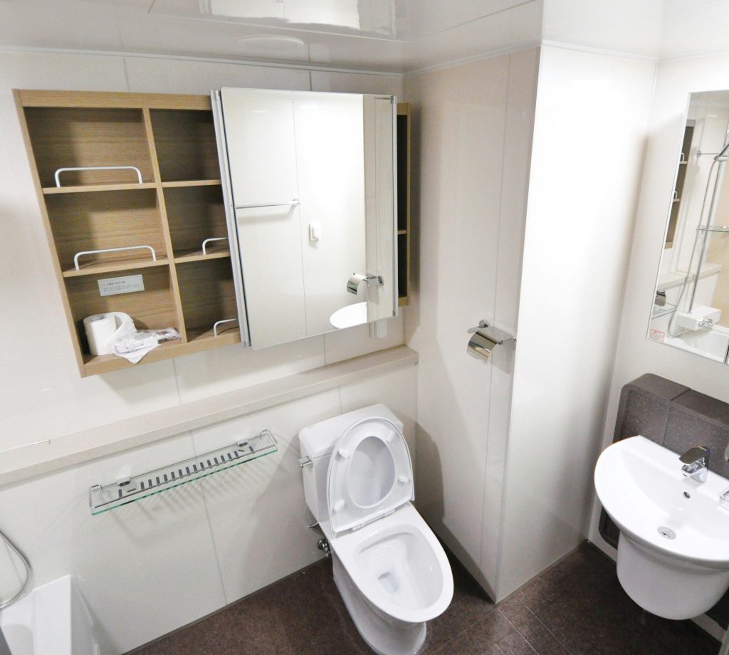 pexels-photo-262005-262005 A contemporary bathroom with a toilet, sink, and storage shelves featuring a minimalist design.