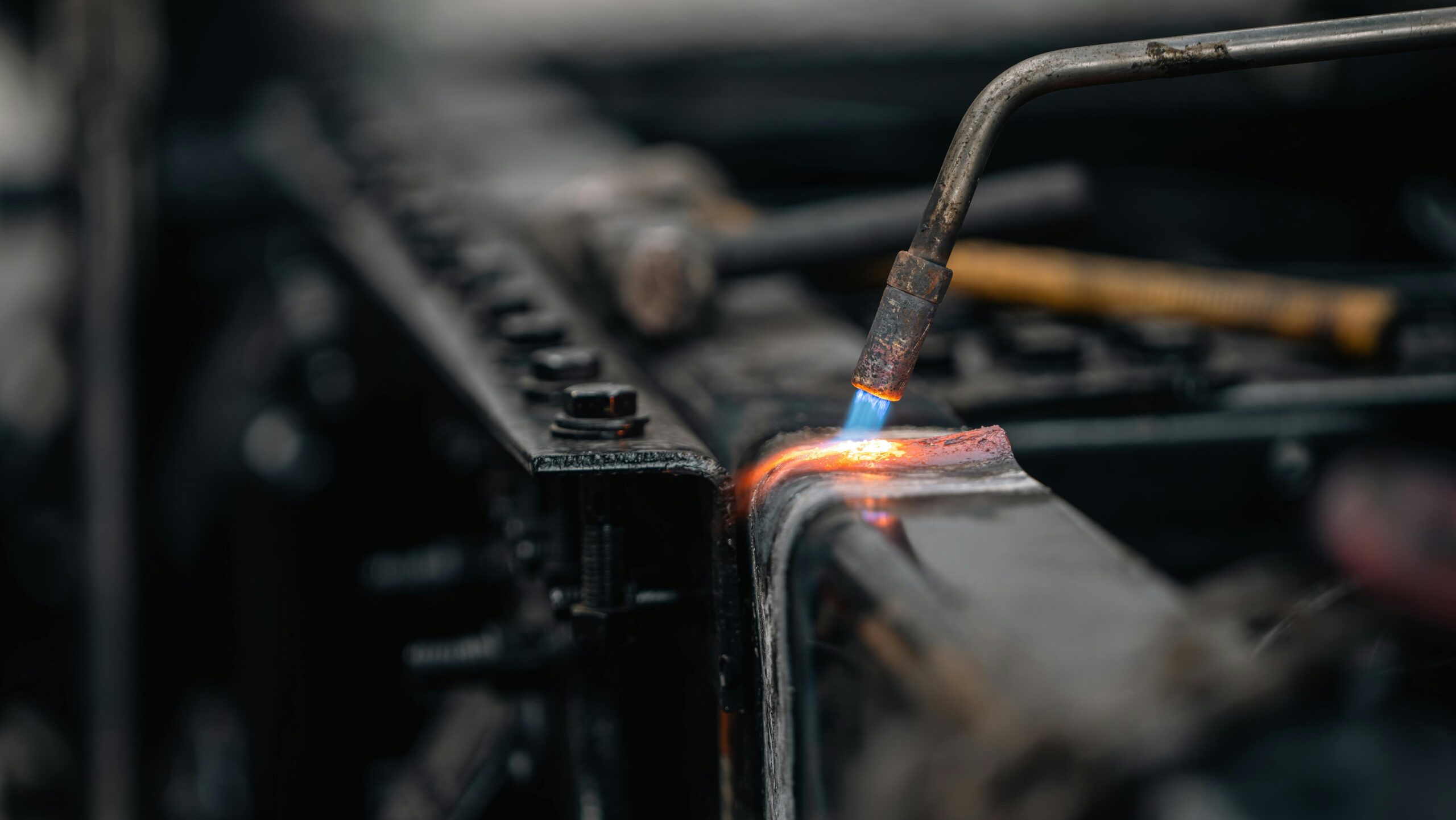 Detailed view of torch welding metal surface, featuring blue flame.